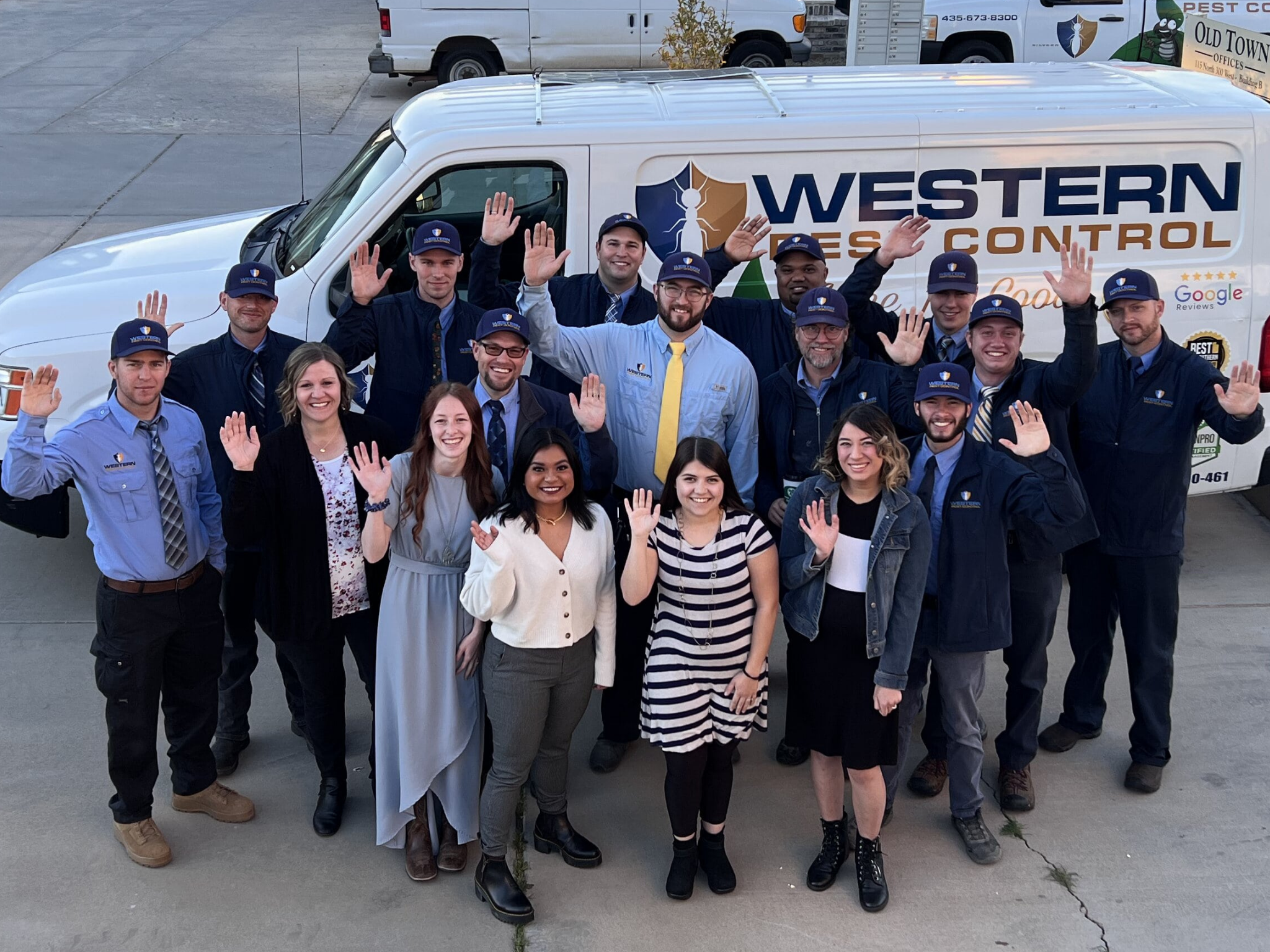 Employees waving in front of a work truck.