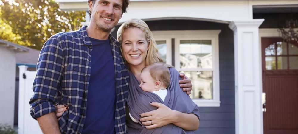 parents and baby outside of house