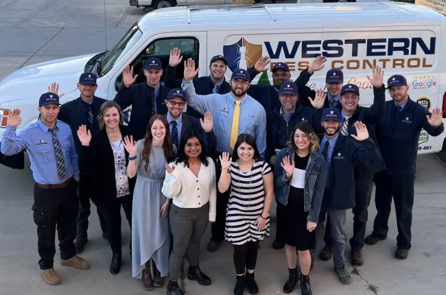 Employees waving in front of a work truck.